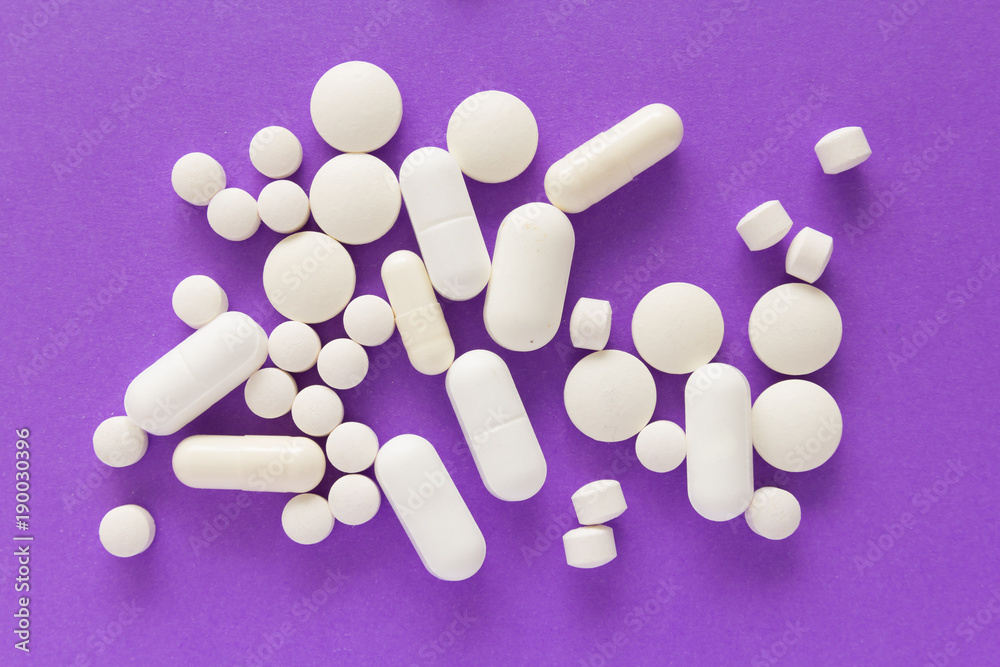 Group of assorted white tablets. Violet background. Group of assorted white tablets. Violet background.