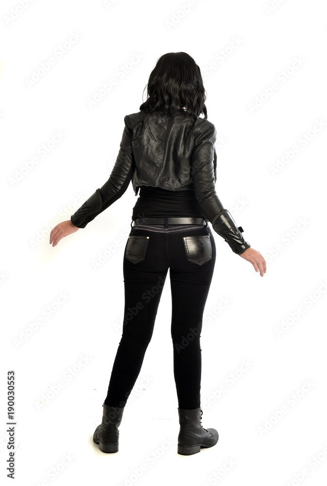 full length portrait of black haired girl wearing leather outfit. standing pose view from behind, on a white background full length portrait of black haired girl wearing leather outfit. standing pose view from behind, on a white background
