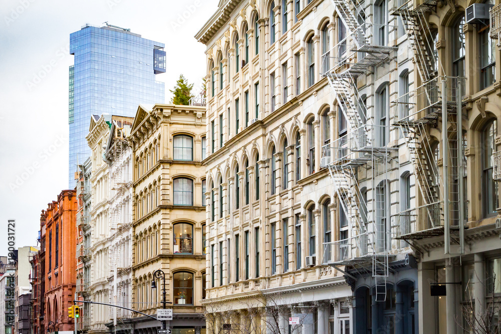 Obraz premium Nowy nowoczesny budynek wznosi się nad starymi zabytkowymi budynkami SoHo na Manhattanie w Nowym Jorku