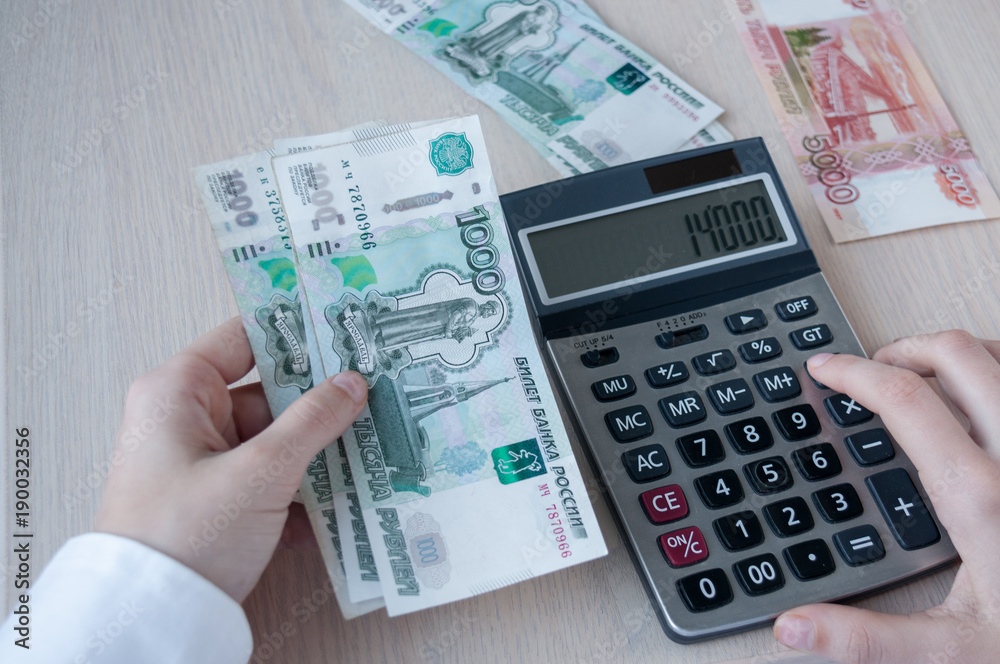 The girl at the table considers the profit with the calculator The girl at the table considers the profit with the calculator