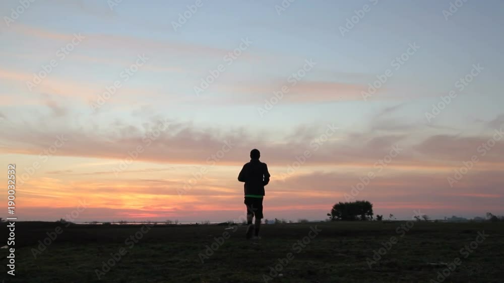 Athletic man running with sunset or sunrise background,moving shot by slider