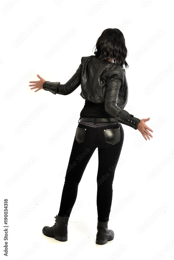 full length portrait of black haired girl wearing leather outfit. standing pose view from behind, on a white background full length portrait of black haired girl wearing leather outfit. standing pose view from behind, on a white background