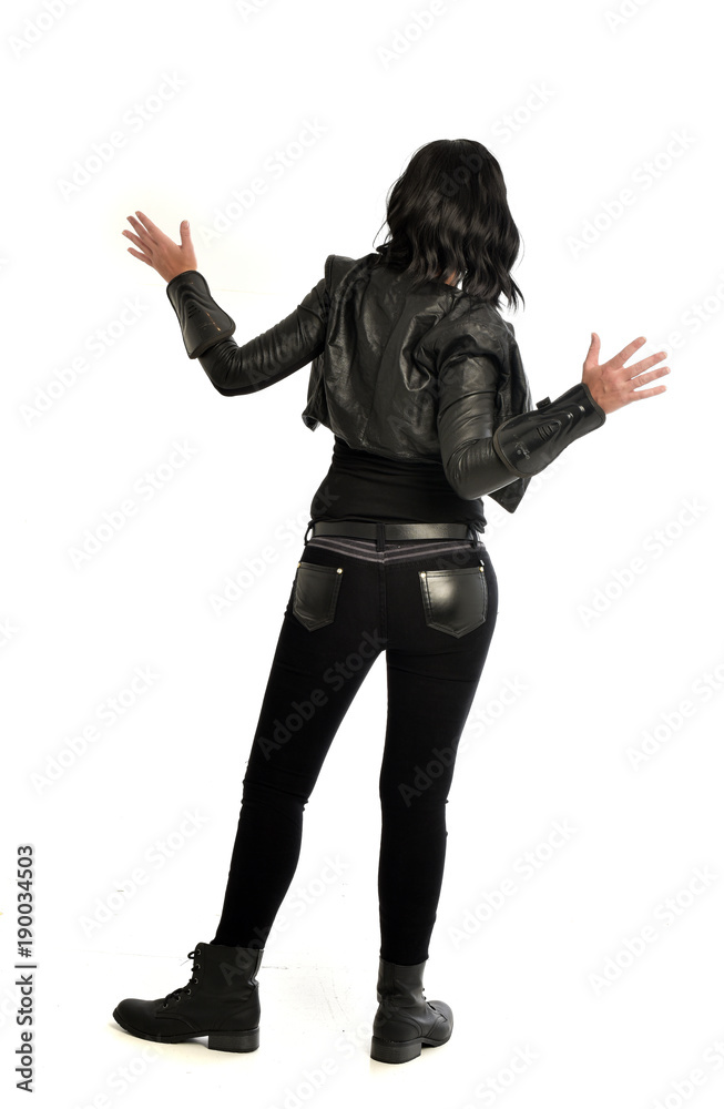 full length portrait of black haired girl wearing leather outfit. standing pose view from behind, on a white background full length portrait of black haired girl wearing leather outfit. standing pose view from behind, on a white background