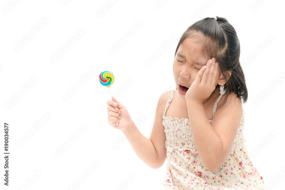 Little Asian girl suffering from toothache and holding candy Little Asian girl suffering from toothache and holding candy