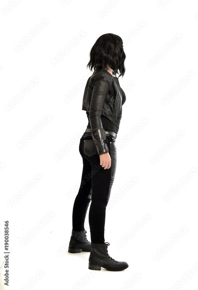 full length portrait of black haired girl wearing leather outfit. standing pose view from behind, on a white background full length portrait of black haired girl wearing leather outfit. standing pose view from behind, on a white background