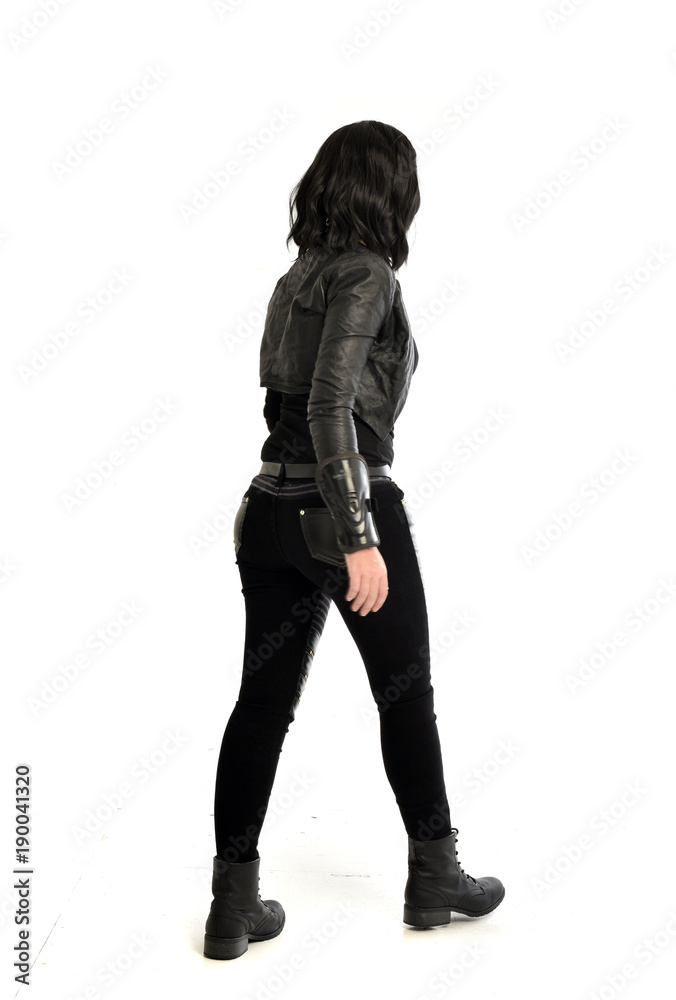 full length portrait of black haired girl wearing leather outfit. standing pose view from behind, on a white background full length portrait of black haired girl wearing leather outfit. standing pose view from behind, on a white background
