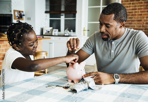 Dad and daughter saving money to piggy bank photo