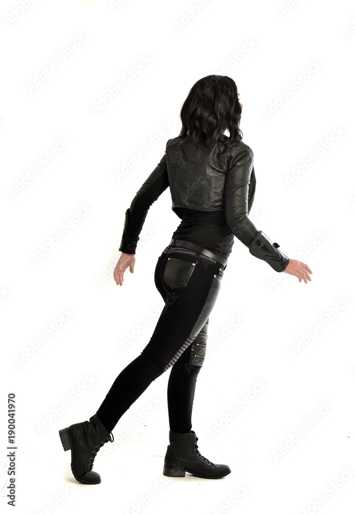 full length portrait of black haired girl wearing leather outfit. standing pose view from behind, on a white background full length portrait of black haired girl wearing leather outfit. standing pose view from behind, on a white background