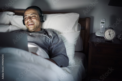 Man using laptop on a bed