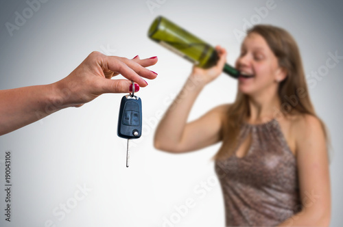 Woman drinking alcohol and her friend showing car keys