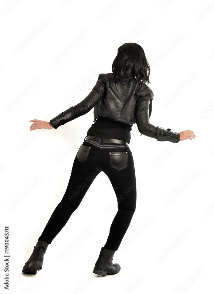 full length portrait of black haired girl wearing leather outfit. standing pose view from behind, on a white background full length portrait of black haired girl wearing leather outfit. standing pose view from behind, on a white background