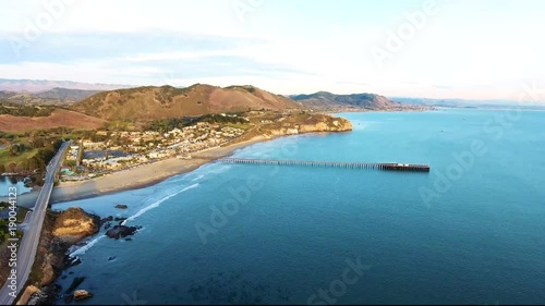 Aerial Flyover - Avila Beach seaside town drone ascending view with a pier and mountains