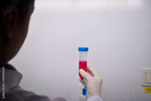 A hand holding a test tube with a purple sample
