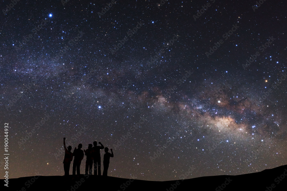 Fototapeta premium landscape with milky way, Night sky with stars and silhouette of a standing sporty man with raised up arms on high mountain.