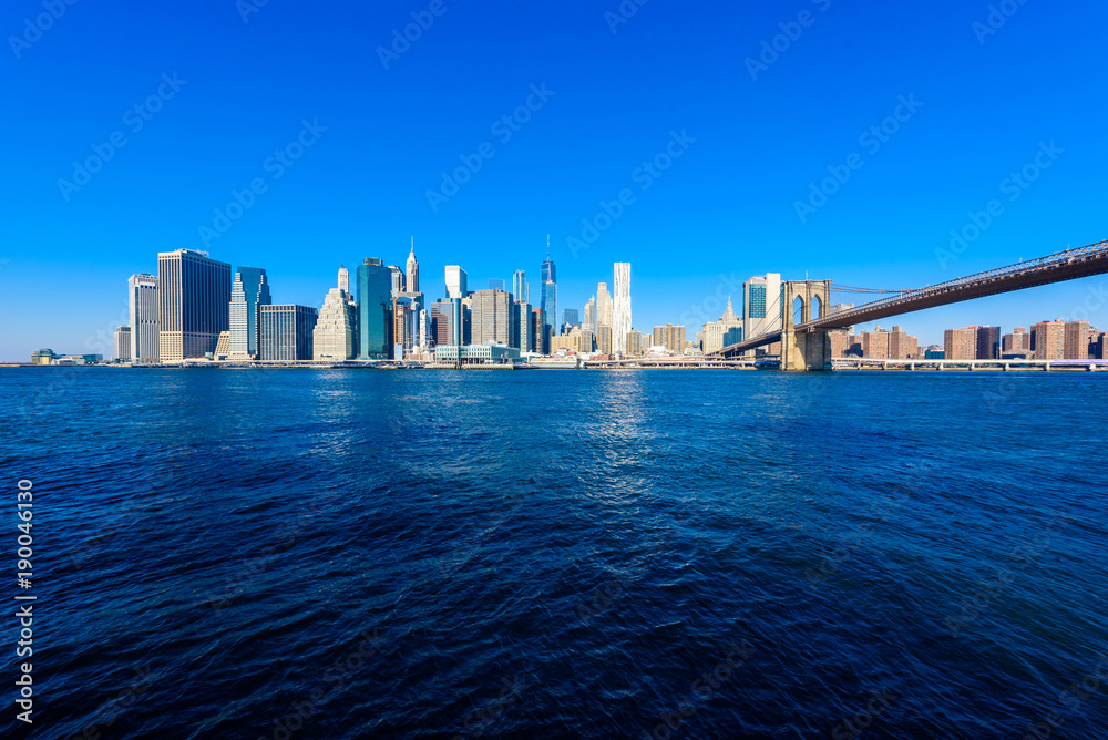Brooklyn Bridge and the Lower Manhattan skyline panorama from Brooklyn Bridge Park riverbank, New York City, USA