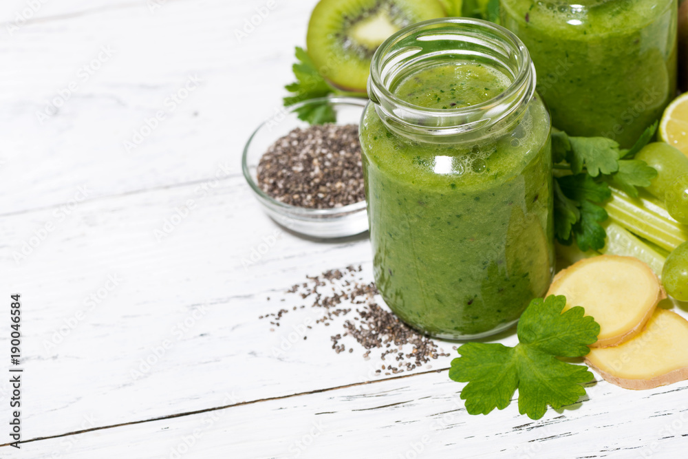 green fruit and vegetable smoothies in jars on white table, top view
