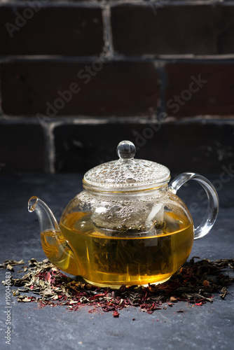 fresh tea in a glass teapot on dark background, vertical
