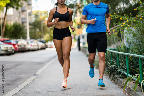 Couple jogging on city street, face cropped.