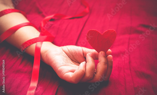 Paper Heart in the hand  on red bed background. holding heart sexy valentine concept