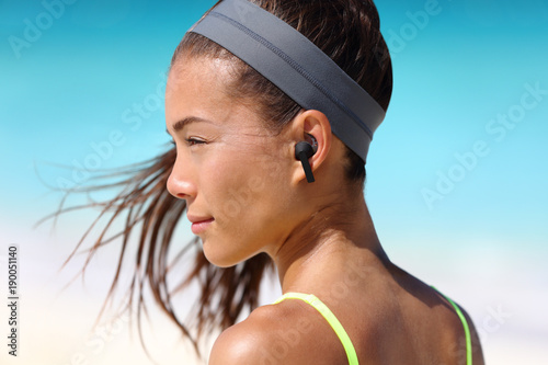 Wireless earbuds woman listening to music on beach photo