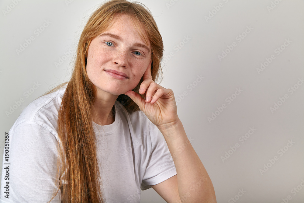Close up studio portrait of young girl with red hair and freckles dressed in boyfriend-styled white t-shirt and looking at the camera Close up studio portrait of young girl with red hair and freckles dressed in boyfriend-styled white t-shirt and looking at the camera