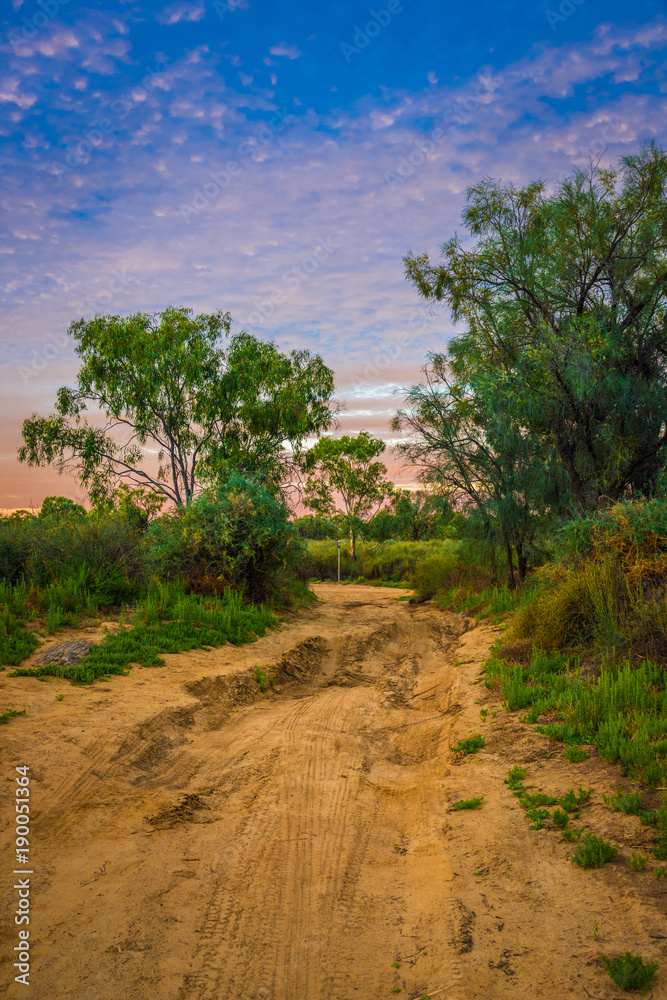 Rural Australian Landscape with colorful clouds ans dirty gravel road in Outback of Australia at sunrise/sunset