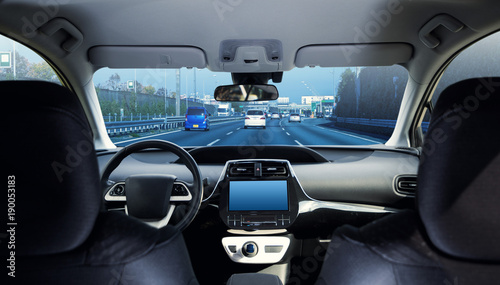 Cockpit of driverless car driving on highway viewed from rear seat.