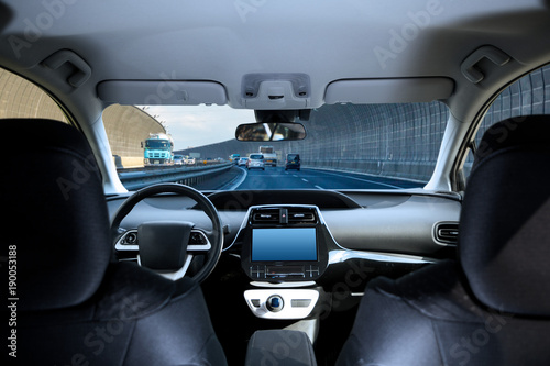 Cockpit of driverless car driving on highway viewed from rear seat. © metamorworks