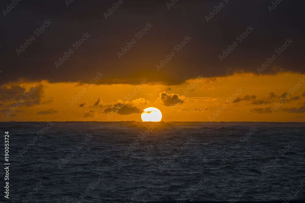Dramatic sunset over ocean waves. Clouds