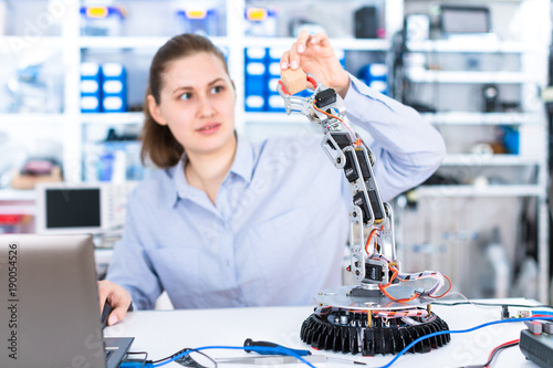 A girl in a University laboratory is experimenting with a robot
