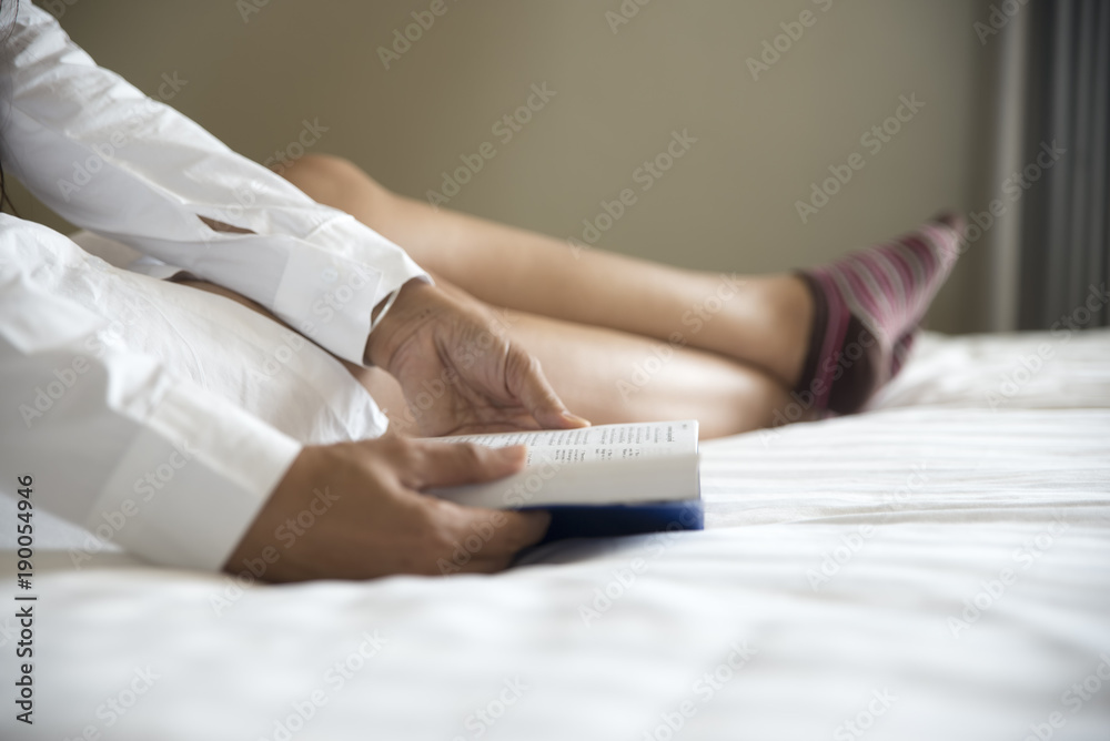 Woman reading book on white bed room,relaxing time.Girl wake up and lying on bed with enjoy a book.Reading book concept Woman reading book on white bed room,relaxing time.Girl wake up and lying on bed with enjoy a book.Reading book concept