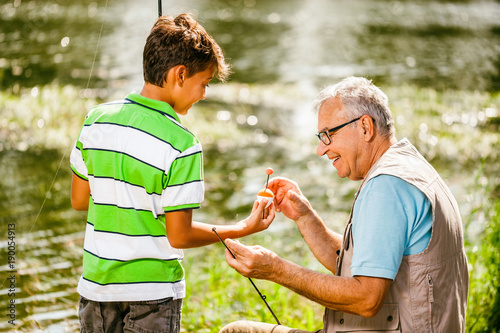 Grandfather and grandson are fishing on sunny day.  © djoronimo