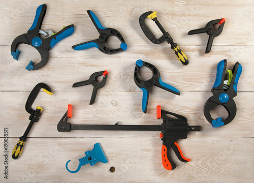 many clamps of different colors lie on a wooden table photo