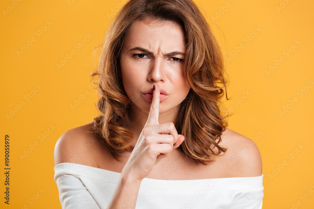 Beautiful young woman showing silence gesture.