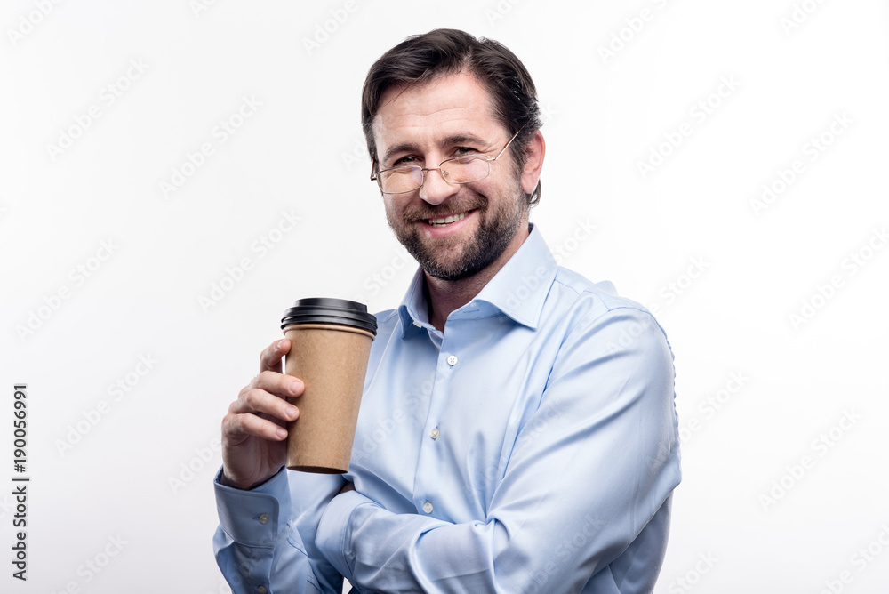 Fantastic taste. Handsome middle-aged man in eyeglasses holding a cup of coffee and posing for the camera while standing isolated on a white background Fantastic taste. Handsome middle-aged man in eyeglasses holding a cup of coffee and posing for the camera while standing isolated on a white background