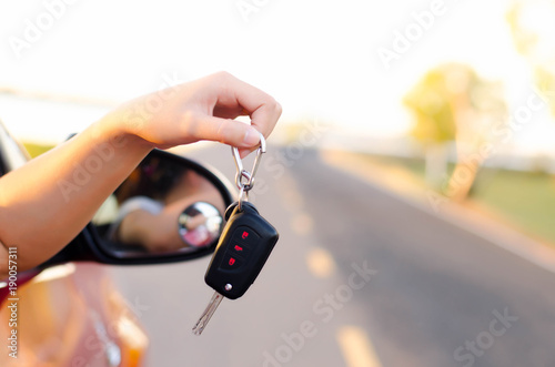 Women show the car keys outside the car window happily.