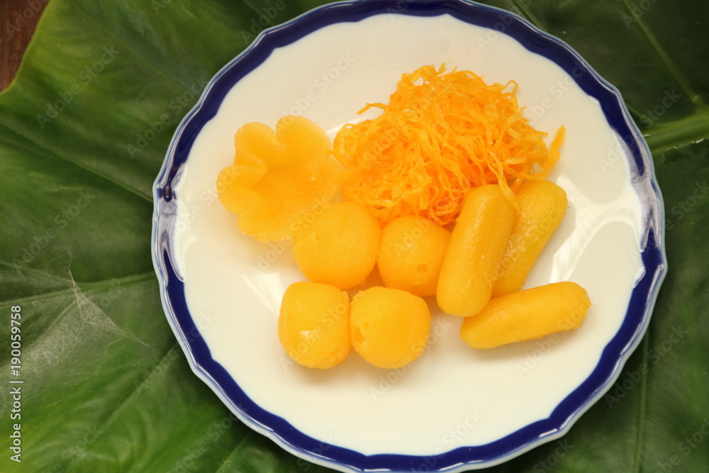 ancient Thai Dessert, thai sweet dessert in plate on green leaf background,egg yoke fudge balls cooked in syrup, Pinched gold egg yolks, appetizer ancient Thai Dessert, thai sweet dessert in plate on green leaf background,egg yoke fudge balls cooked in syrup, Pinched gold egg yolks, appetizer