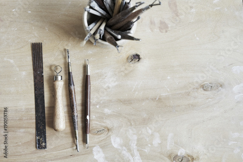 Ceramic working process, clay and tools for hand-crafted work. View from above, wooden table