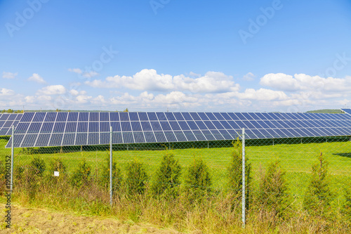 Solar energy panels on green field, blue sky