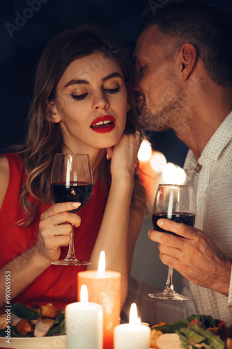 Curious lady in dress red with glass of wine listening her handsome man