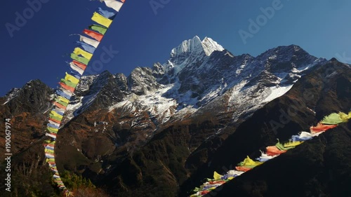 Multi-colored Buddhist flags ripple in the wind against the background of snow-capped mountains