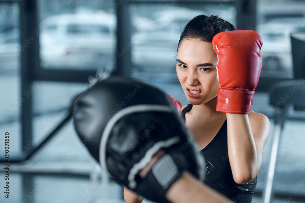 female boxer exercising with trainer at gym