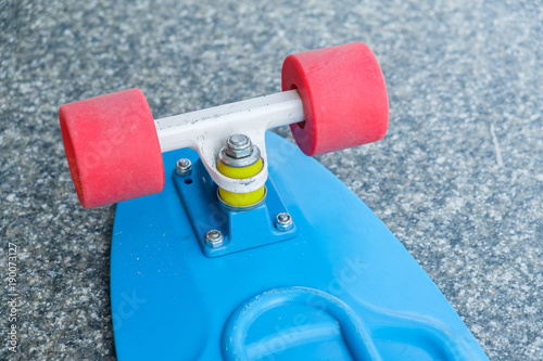 Back of blue plastic skate board. Red wheels. photo