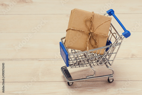 Shopping cart with gift box wrapped with paper kraft on table.