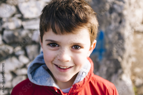 portrait of 9 year old boy with red jacket outside