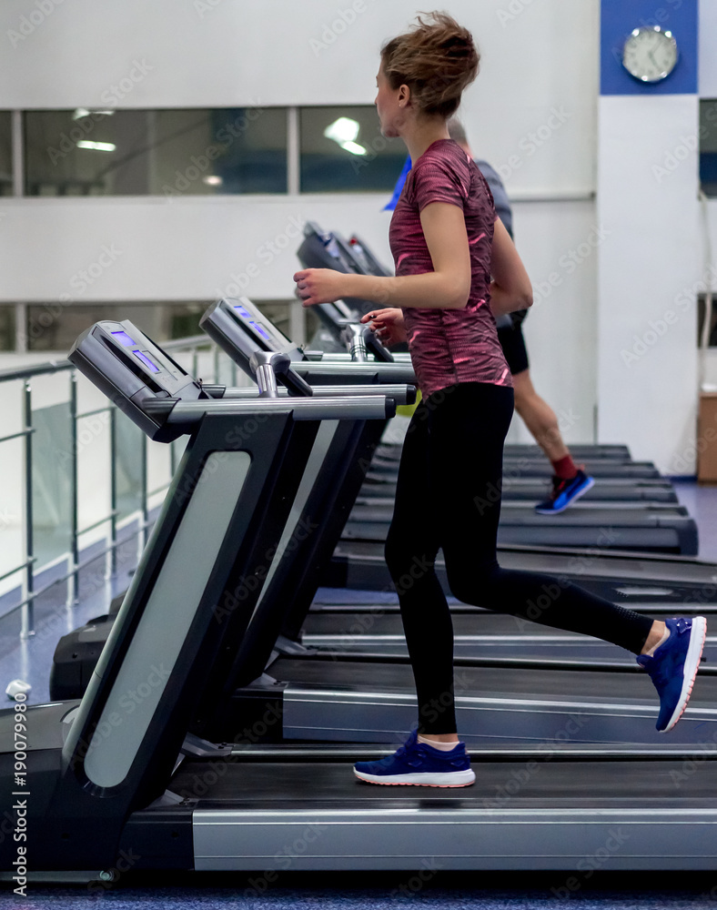 Young model girl makes exercises at the gym in front of mirror