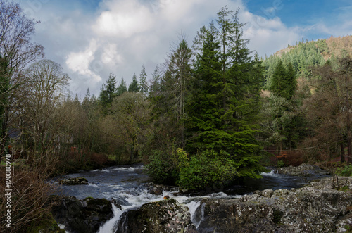 Beautiful river scene with trees on a small island and a waterfall in the foreground at the village of Betws Y Coed in North Wales