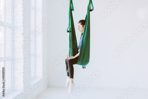 Woman sitting iin hammock before practicing aerial yoga in white loft interior studio. photo