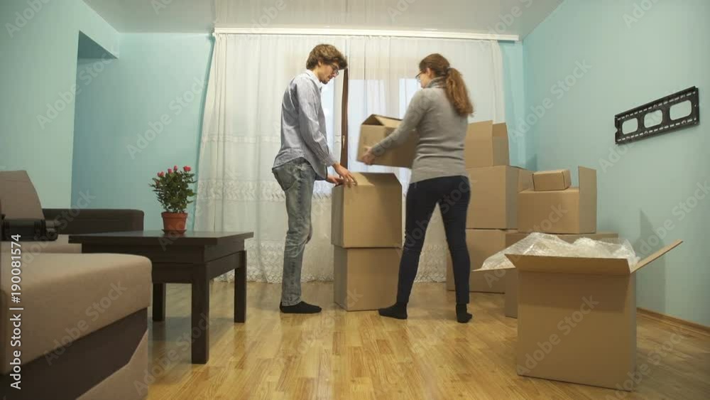 Young couple collects things in a box for moving to a new apartment Young couple collects things in a box for moving to a new apartment