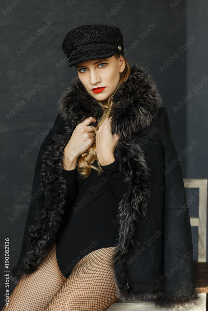 portrait of attractive lady in a black cap and a sheepskin coat with a fur collar . Perfect makeup, red lips and blue eyes portrait of attractive lady in a black cap and a sheepskin coat with a fur collar . Perfect makeup, red lips and blue eyes